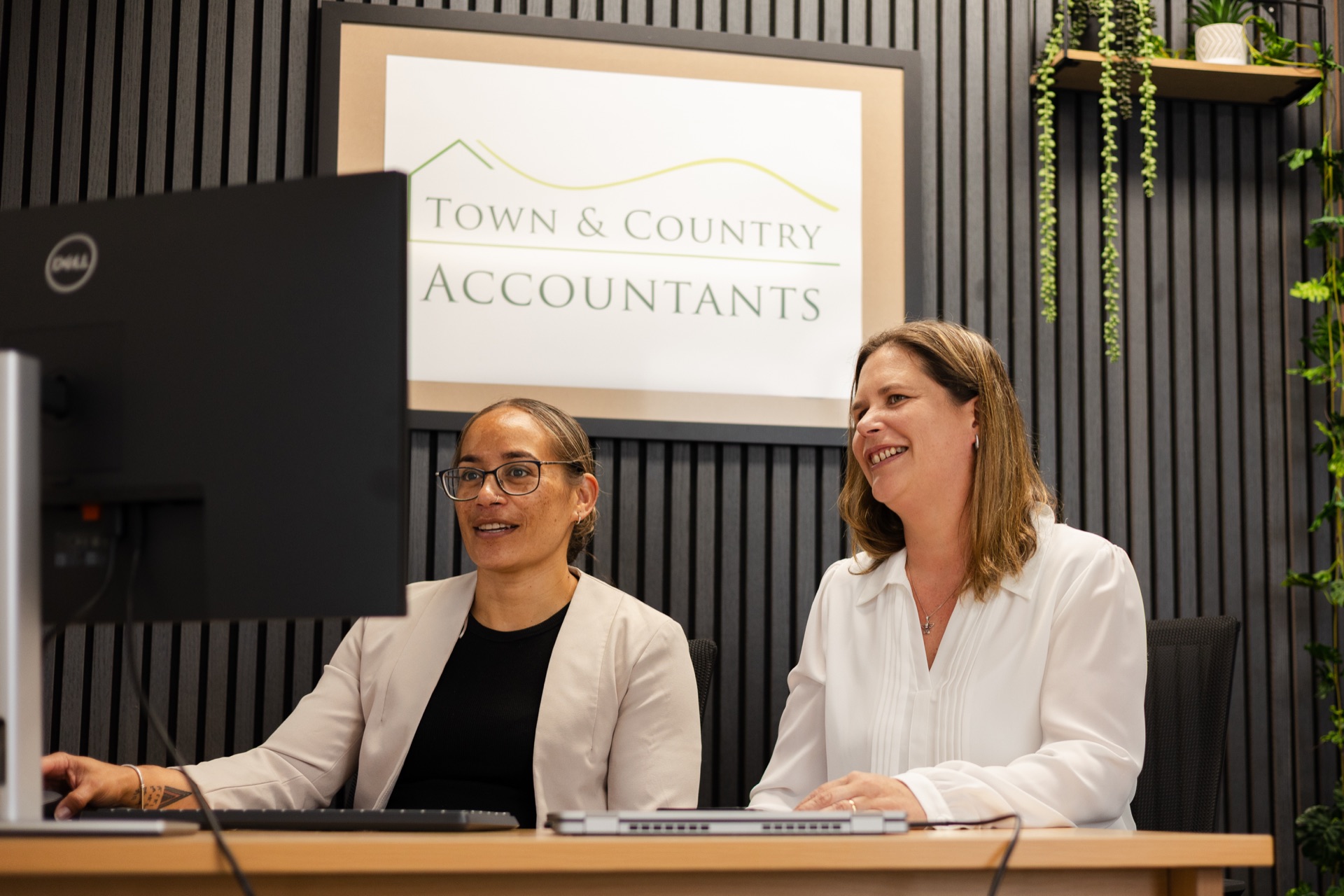 Chelsea and Veronica from TACA at the office desk, with the Town and Country Accountants sign behind them